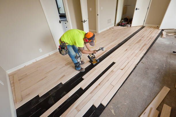 A workman installing a maple hardwood floor in a residential home construction.
